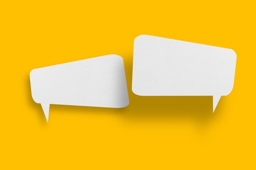 White paper in speech bubble shape set against yellow background. photo