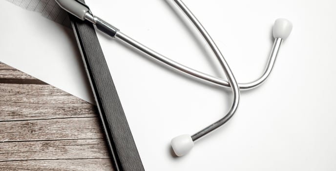 Stethoscope in doctors desk and paper folder on wooden background photo