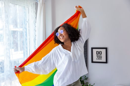 African American girl holding LGBTQ rainbow flag in her bed room for coming out of the closet and pride month celebration to promote sexual diversity and equality in homosexual orientation concept photo