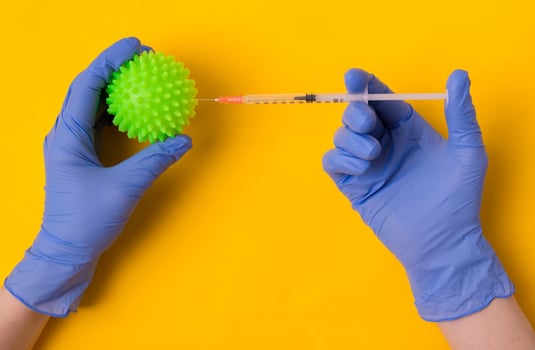 Hands in blue surgical gloves hold a coronavirus molecule on a yellow background. photo