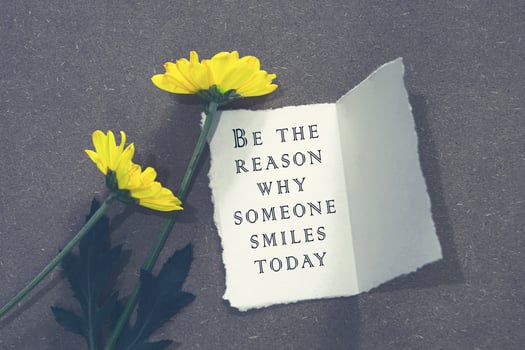 Motivational and inspiratinal quote on white paper with flowers on wooden desk. photo