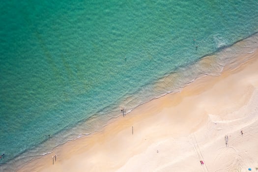 Aerial view sandy beach and waves People relaxing on beach Beautiful tropical sea in the morning summer season image by Aerial view drone shot, high angle view Top down sea waves photo