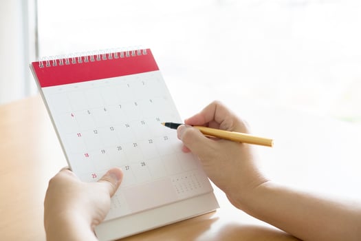 Woman hand carrying calendar and pointing on it by pen photo