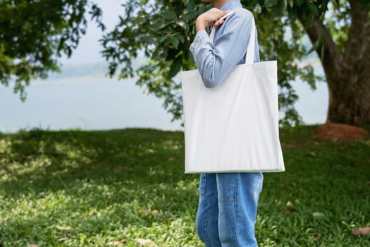 young woman holding cotton bag in green background photo