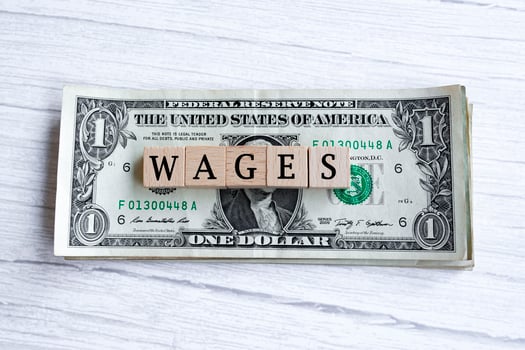 Wages word written on wood block with American Dollar-bills. Directly above. photo
