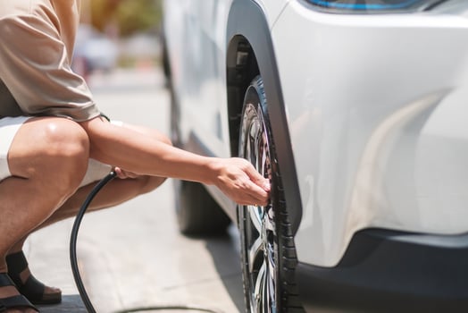 man driver hand inflating tires of vehicle, removing tire valve nitrogen cap for checking air pressure and filling air on car wheel at gas station. self service, maintenance and safety photo