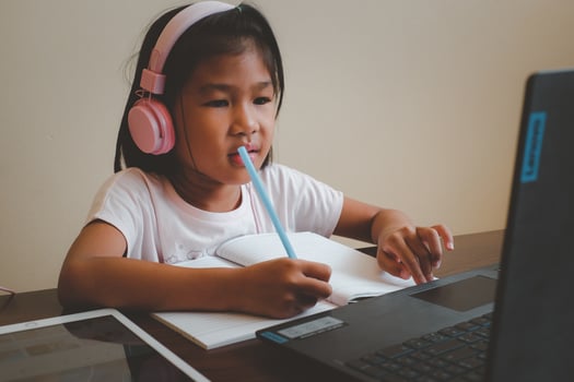 Thai girl in online learning class at home during the COVID-19 situation. Student writing the book and learning form notebook during quarantine. Selected focus. Online education, home school concept. photo