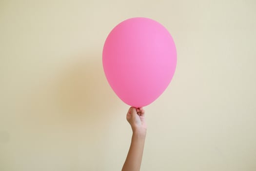 Close up hand's kid holding the pink balloon isolated on white background. photo