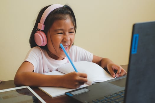 Thai girl in online learning class at home during the COVID-19 situation. Student writing the book and learning form notebook during quarantine. Selected focus. Online education, home school concept. photo