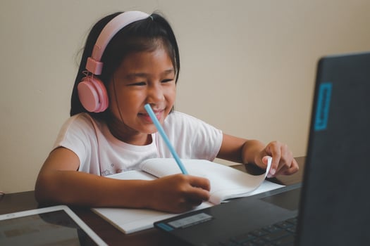 Thai girl in online learning class at home during the COVID-19 situation. Student writing the book and learning form notebook during quarantine. Selected focus. Online education, home school concept. photo