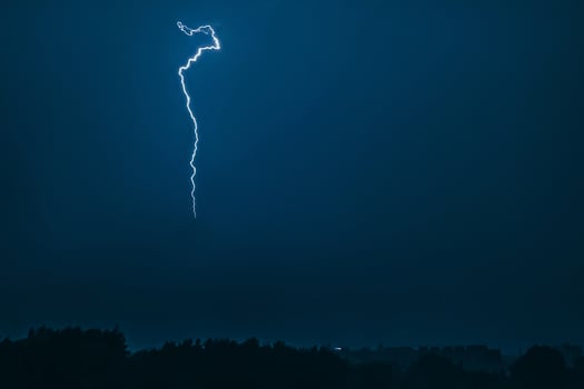 Lightning in sky over city. Bright flashes on dark night. Thunderclouds and electricity discharges in  atmosphere. photo
