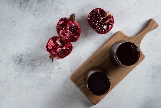 Two cups of fresh pomegranate juice on a wooden board photo