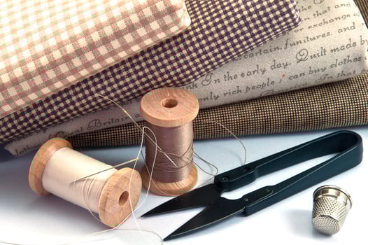 Sewing accessory including thread spool, needle, scissor, thimble, and cloth on white background photo