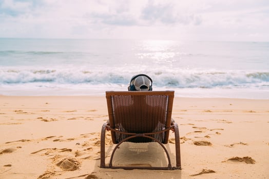 summer holidays, technology and internet concept. latin american man sitting on the beach chair, listen music with headphone and sunning on the beach photo