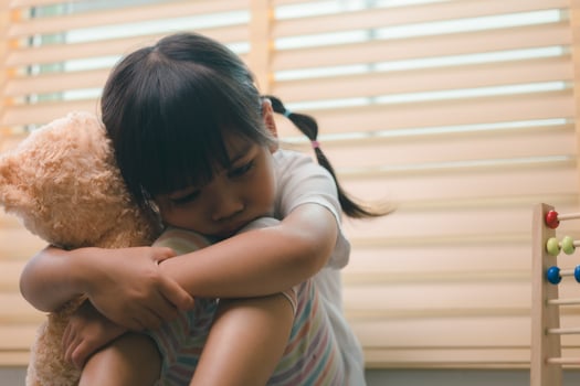 Close up lonely little girl hugging toy, sitting at home alone, upset unhappy child waiting for parents, thinking about problems, bad relationship in family, psychological trauma photo