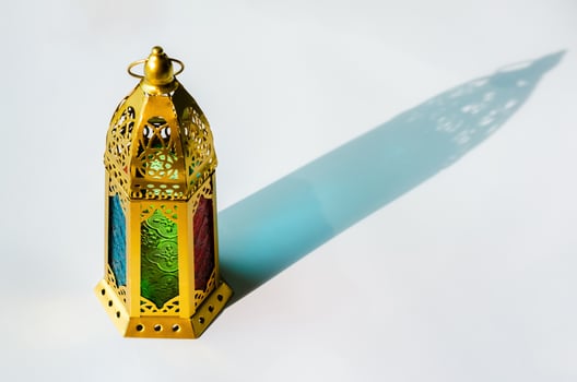 Golden lantern with shadow from sun light on white background. photo