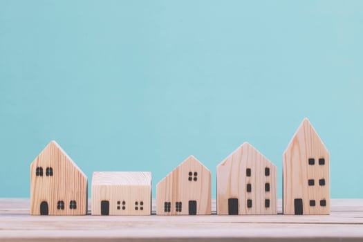 Building different wood house model on blue background , managing property investment concept photo