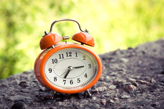 Vintage style orange alarm clock on a concrete surface. photo
