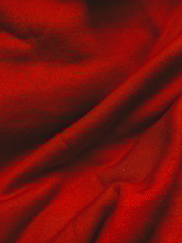 Red fabric cloth texture background with wavy folds and shadows, closeup, vertical photo. Abstract textile material, elegant wallpaper design, top view photo