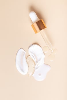 Top drops and smears of cream cosmetics with a pipette on a beige background photo