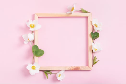 Summer or spring composition on a pink background. Wooden frame with anemone flowers with copy space. Summer, spring floral concept photo