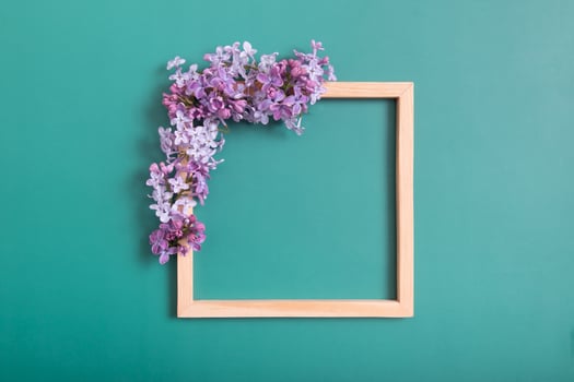 Summer or spring composition on a green background. Lilac flowers with wooden square with copy space top view. Summer, spring floral concept. photo