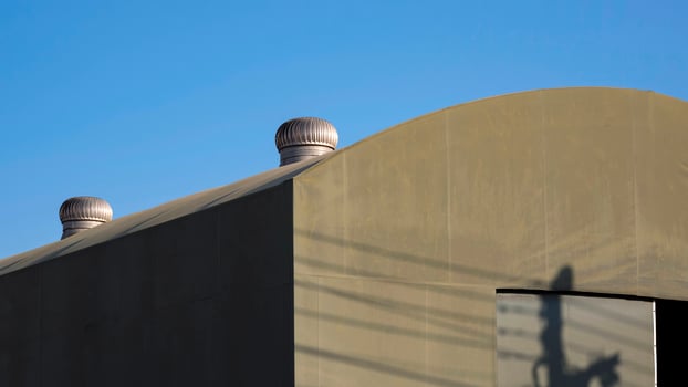 Selective focus at roof ventilators on top of the old tent warehouse against blue sky background photo