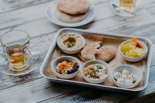 Overhead image of traditional Israel food on tray. Hummus, domestic goat cheese, tomatoe core, beetroot with spices, pita bread, beverage in glass photo