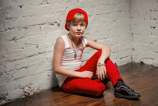 Portrait of cool young hip hop boy in red hat and red pants and white shirt in the loft photo