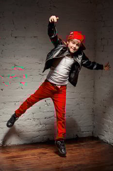 Portrait of cool young hip hop boy in red hat and red pants and white shirt and black leather jacket in the loft photo