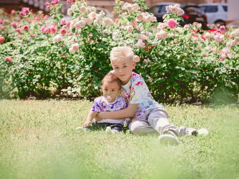 caucasian adorable cute boys siblings holding each other in sunny day outdoor. Family, help, support concept photo