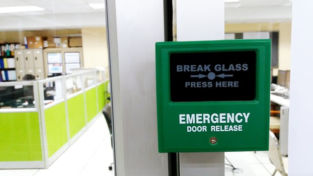 Close up green emergency door release to escape from the inside room with blurred office background photo