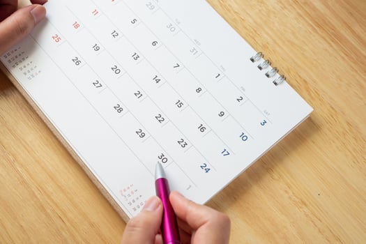 calendar page with female hand holding pen on desk table photo