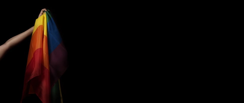 LGBTQ pride flag on black background. Lgbt rainbow flag in gay hand. photo