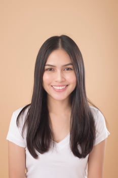 A Portrait of Asian woman with white T-shirt over Light brown background studio photo
