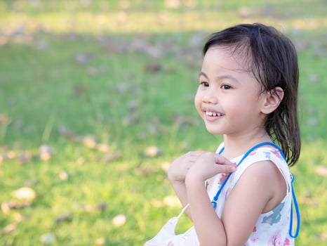 Positive charming 4 years old cute baby Asian girl, little preschooler child smiling and looking to the left photo