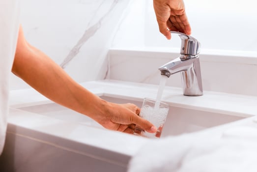 Man filling glass of water at sink in bathroom. photo
