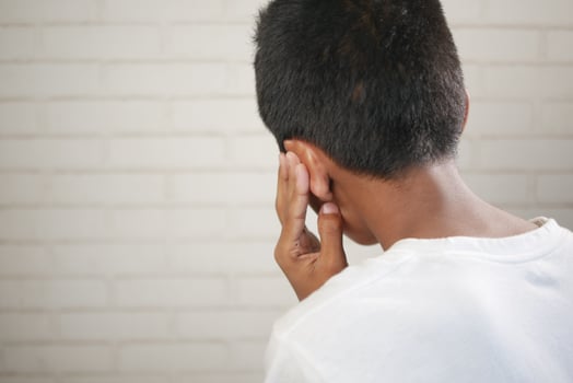 teenage boy having ear pain touching his painful ear , photo