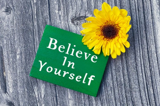 Believe in yourself word on green wooden cube with and sunflower. photo