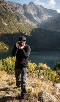 Young  man photographer taking photographs with digital camera in a mountains. photo