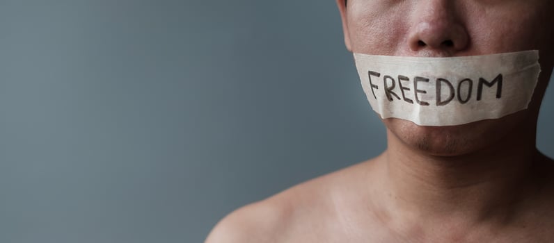 Man with mouth sealed in adhesive tape with Freedom message. Free of speech, freedom of press, Human rights, Protest dictatorship, democracy, liberty, equality and fraternity concepts photo