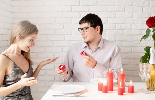 handsome man putting wedding ring on and proposing to his beautiful woman in cafe photo