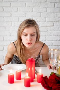 young woman blowing out candle on romantic date table photo