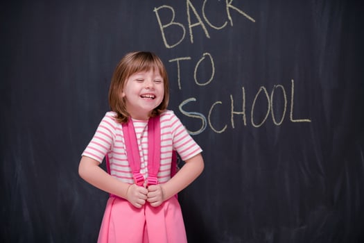 school girl child with backpack writing  chalkboard photo