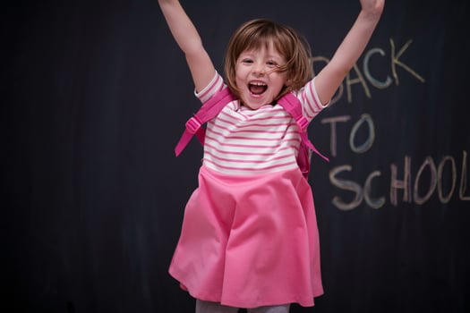 school girl child with backpack writing  chalkboard photo
