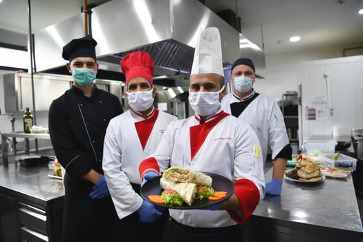 group chefs standing together in the kitchen at restaurant wearing protective medical mask and gloves in coronavirus new normal concept photo