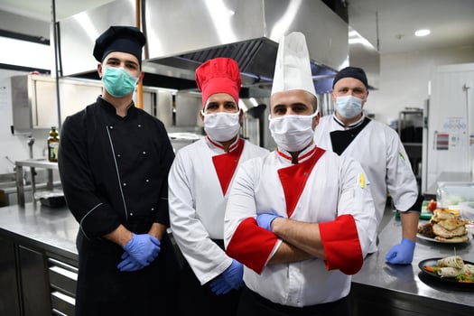 group chefs standing together in the kitchen at restaurant wearing protective medical mask and gloves in coronavirus new normal concept photo