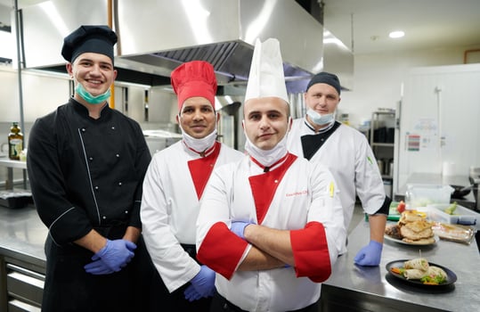 group chefs standing together in the kitchen at restaurant wearing protective medical mask and gloves in coronavirus new normal concept photo