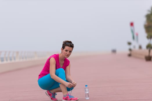 Young woman tying shoelaces on sneakers photo