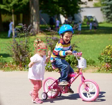 Boy and girl in park learning to ride a bike photo